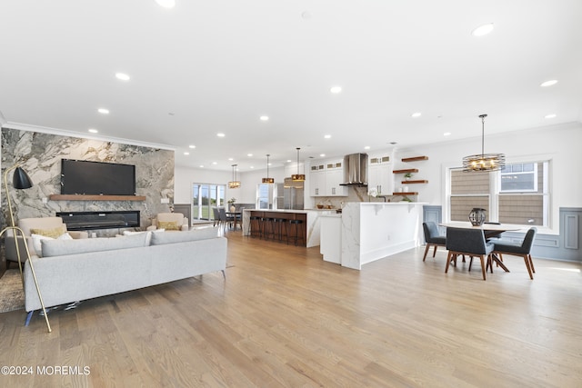 living room featuring light wood-type flooring, a fireplace, and crown molding