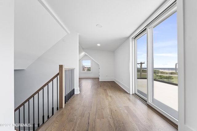 corridor featuring lofted ceiling and light hardwood / wood-style flooring