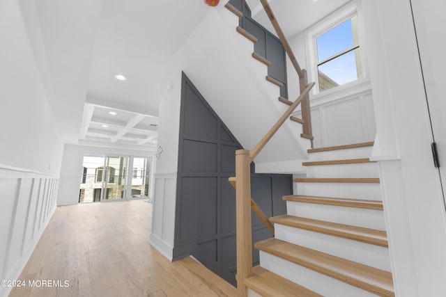 stairs with wood-type flooring, beamed ceiling, and coffered ceiling