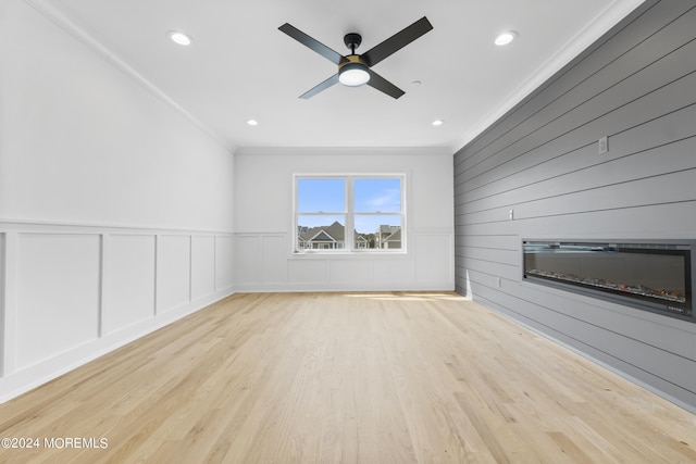 unfurnished living room with ceiling fan, light wood-type flooring, and crown molding