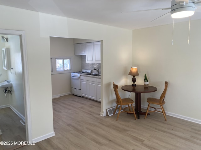 dining area with ceiling fan, sink, and light hardwood / wood-style flooring