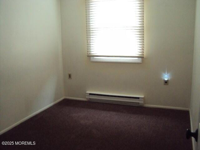 carpeted empty room with a baseboard heating unit