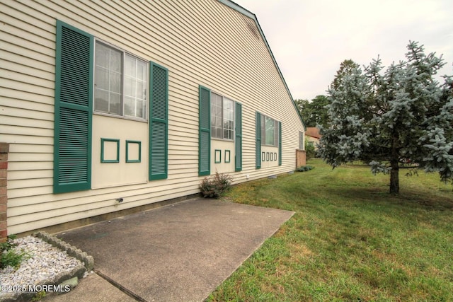 view of side of property featuring a patio area and a lawn