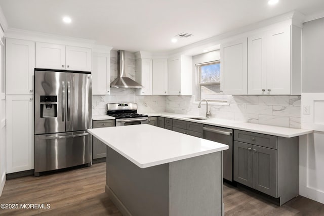 kitchen with appliances with stainless steel finishes, dark hardwood / wood-style floors, a center island, wall chimney range hood, and sink