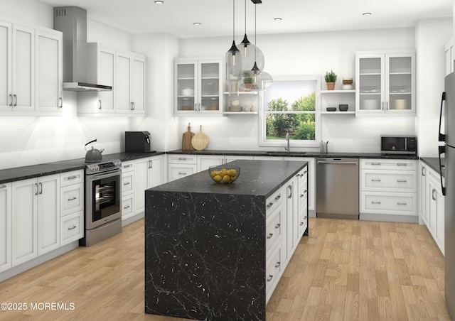 kitchen with pendant lighting, light hardwood / wood-style floors, wall chimney range hood, and stainless steel appliances