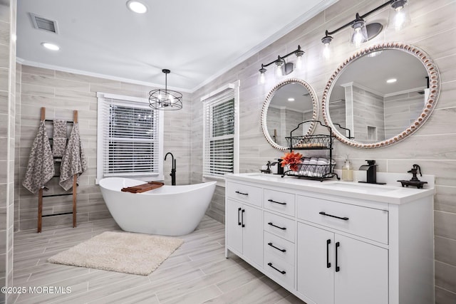 bathroom with vanity, tile walls, a notable chandelier, crown molding, and a bathtub