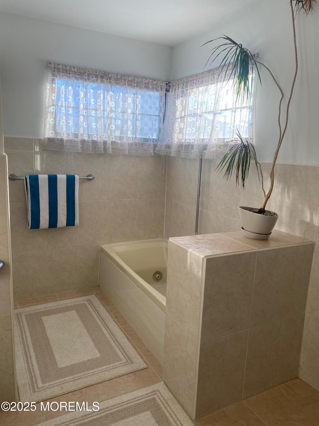 bathroom featuring tile patterned floors, a bathtub, and tile walls