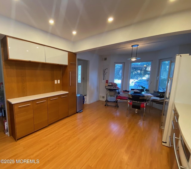 kitchen featuring white fridge, white cabinets, light wood-type flooring, and decorative light fixtures