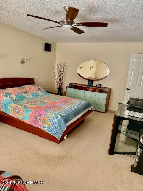 bedroom with ceiling fan, carpet floors, and a textured ceiling