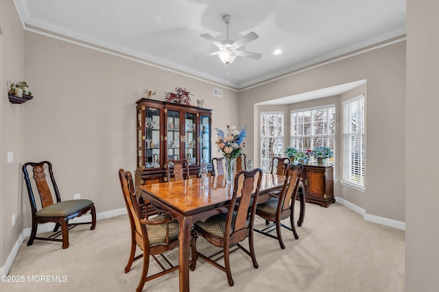 carpeted dining room featuring ceiling fan and crown molding