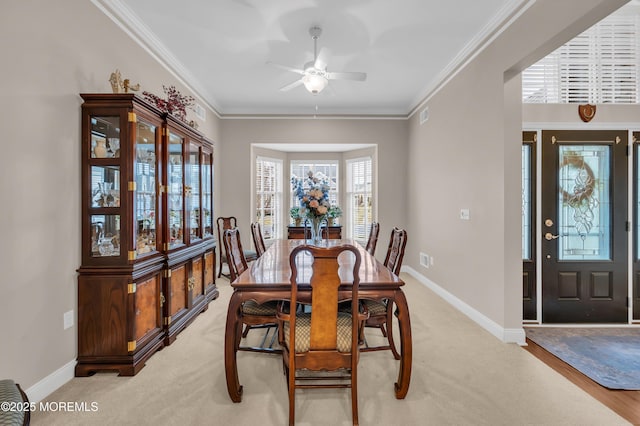 carpeted dining room featuring ceiling fan and ornamental molding