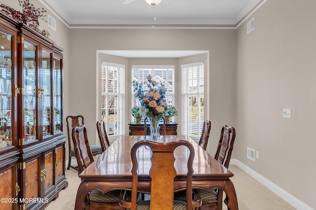 carpeted dining room with ceiling fan and ornamental molding