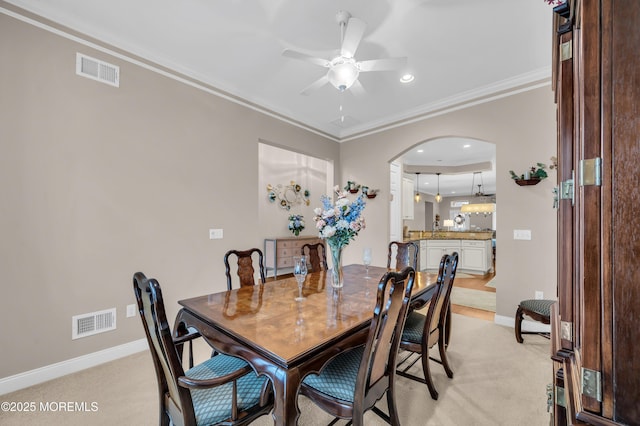 carpeted dining room with ceiling fan and ornamental molding