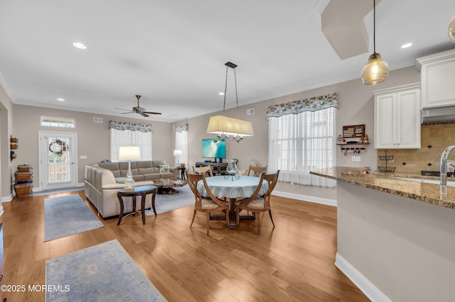 dining space featuring light wood-type flooring, ceiling fan, and ornamental molding