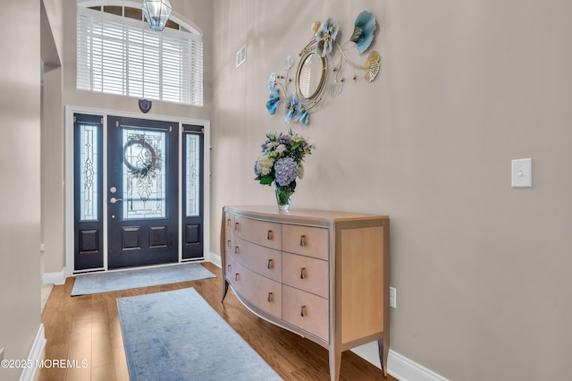 entrance foyer with light hardwood / wood-style flooring and a towering ceiling