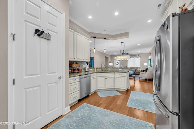 kitchen featuring pendant lighting, kitchen peninsula, white cabinetry, light wood-type flooring, and appliances with stainless steel finishes