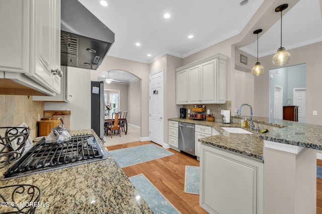 kitchen featuring exhaust hood, kitchen peninsula, sink, white cabinetry, and appliances with stainless steel finishes