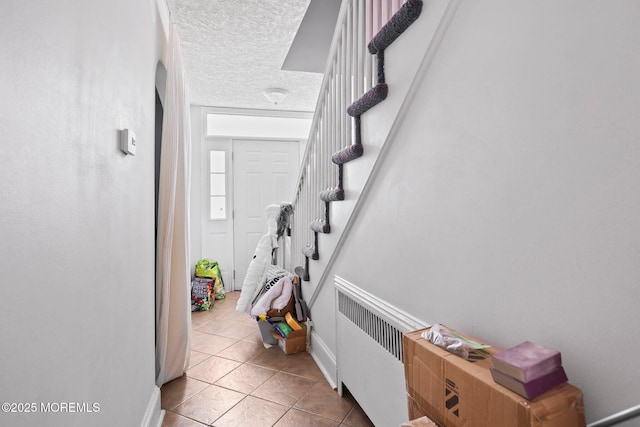 stairway with a textured ceiling, tile patterned floors, and radiator heating unit