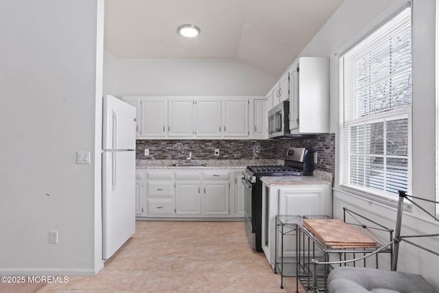 kitchen featuring sink, white cabinetry, vaulted ceiling, and stainless steel appliances