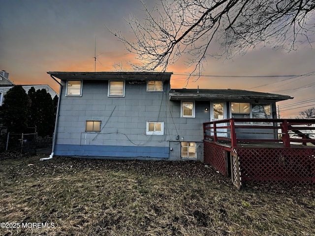 back house at dusk featuring a wooden deck