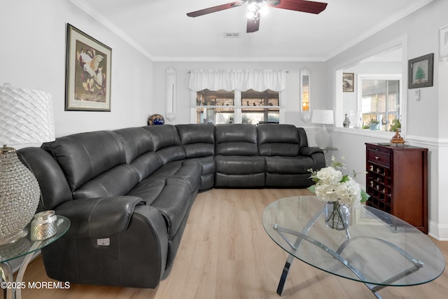 living room with ornamental molding, ceiling fan, and light wood-type flooring