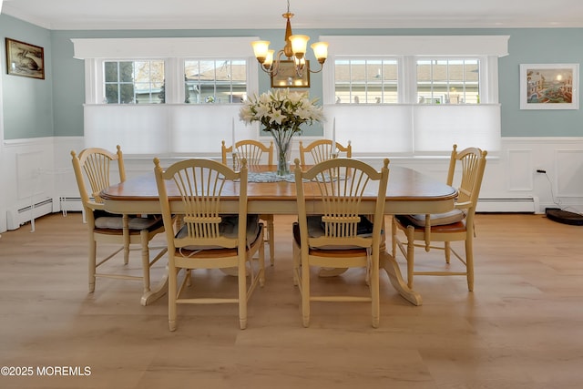 dining space featuring crown molding, light wood-type flooring, and baseboard heating