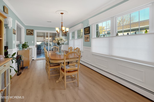 dining room featuring a notable chandelier, ornamental molding, light hardwood / wood-style floors, and baseboard heating