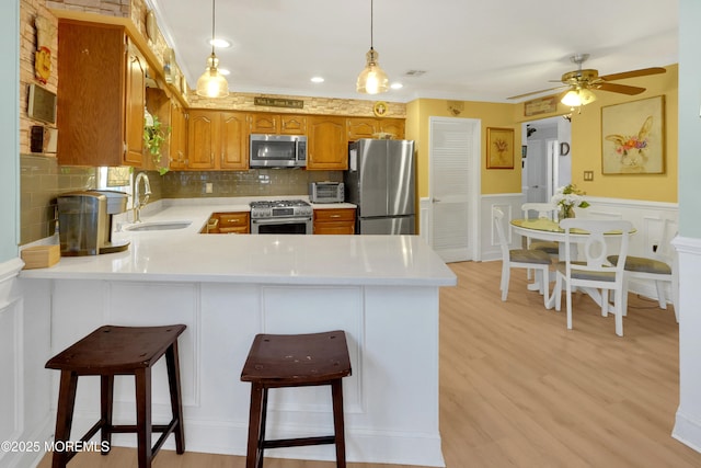 kitchen with sink, a breakfast bar area, hanging light fixtures, kitchen peninsula, and stainless steel appliances