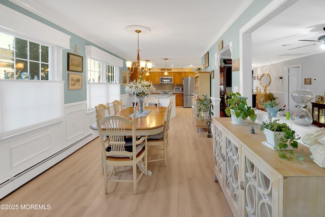 dining room featuring crown molding, a baseboard heating unit, ceiling fan with notable chandelier, and light hardwood / wood-style floors