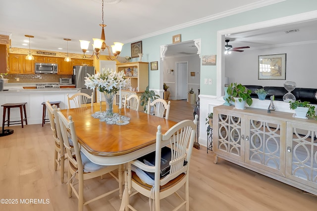 dining space featuring ornamental molding, ceiling fan with notable chandelier, and light hardwood / wood-style flooring