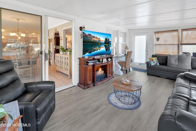 living room with an inviting chandelier, ornamental molding, and hardwood / wood-style floors