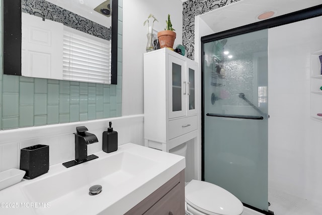 bathroom featuring a shower with door, vanity, and toilet