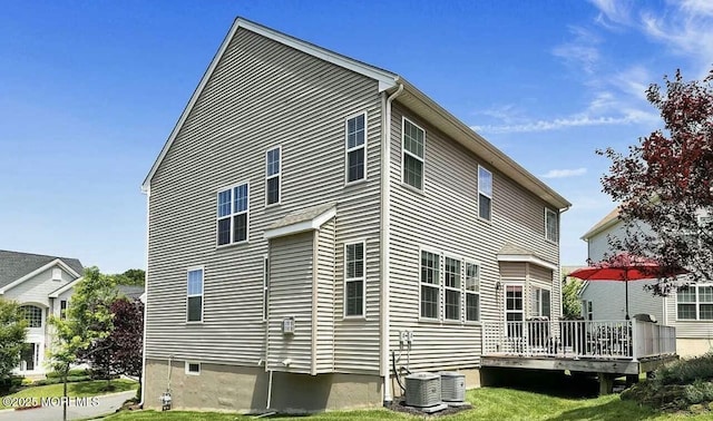 rear view of house featuring a deck, central AC unit, and a lawn