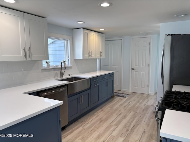 kitchen with light hardwood / wood-style floors, decorative backsplash, sink, white cabinetry, and stainless steel appliances