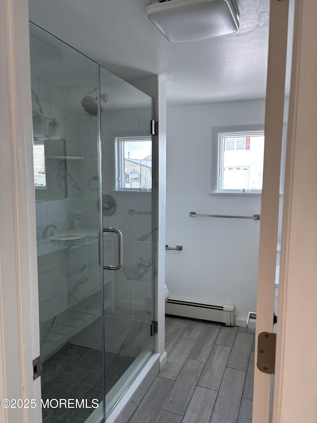 bathroom featuring a baseboard heating unit, toilet, and an enclosed shower