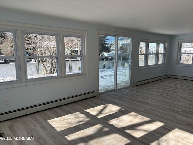 interior space featuring baseboard heating, plenty of natural light, and wood-type flooring