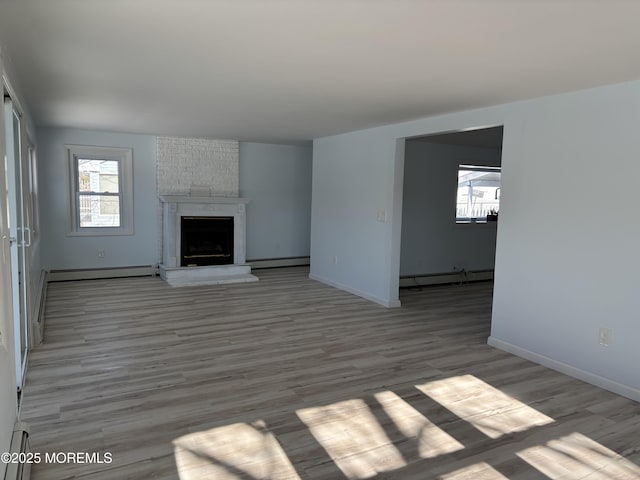 unfurnished living room with light hardwood / wood-style floors, baseboard heating, and a fireplace