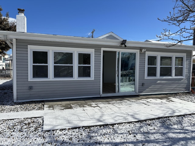 snow covered back of property featuring a patio area