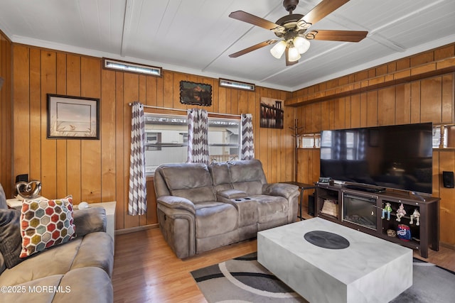 living room featuring wooden walls, ceiling fan, and light hardwood / wood-style flooring