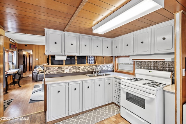 kitchen featuring wood walls, white cabinetry, sink, white range with gas cooktop, and wood ceiling