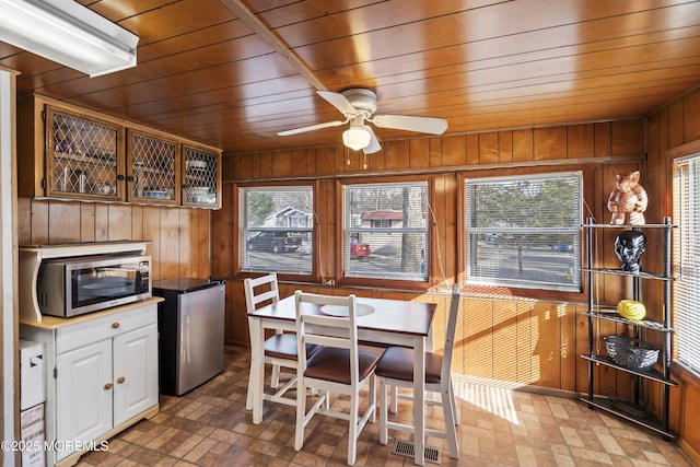 dining area featuring wooden walls, wooden ceiling, and ceiling fan