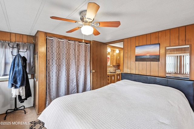 carpeted bedroom featuring ceiling fan and wooden walls