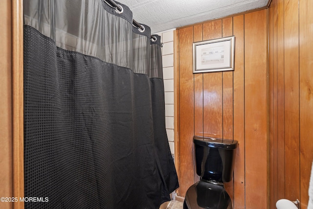 bathroom featuring wooden walls and a textured ceiling