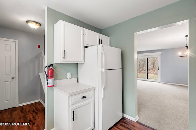 kitchen featuring white refrigerator, dark carpet, white cabinetry, and decorative light fixtures