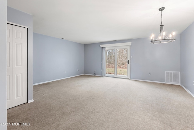 empty room featuring carpet flooring and a notable chandelier