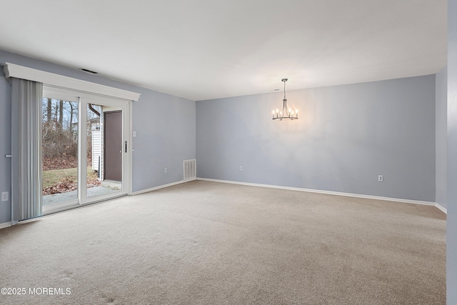 spare room with carpet and an inviting chandelier