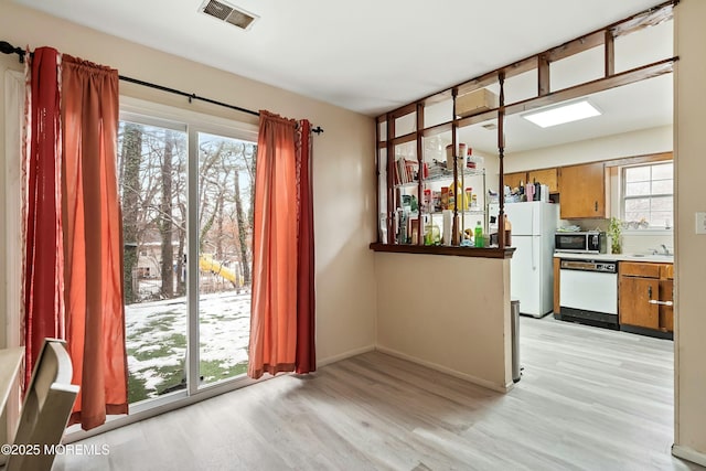 unfurnished dining area with sink, light hardwood / wood-style floors, and a wealth of natural light