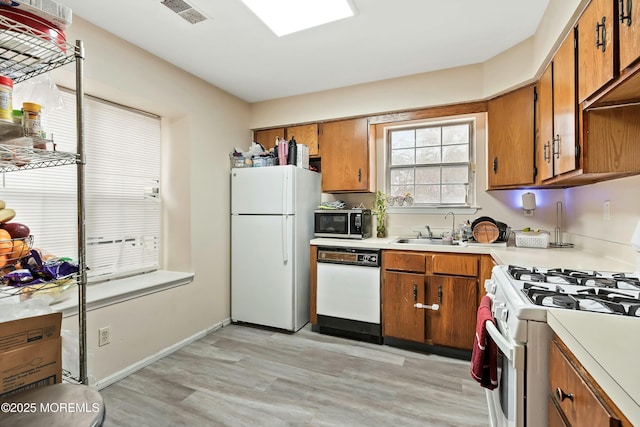 kitchen with sink, white appliances, and light hardwood / wood-style floors