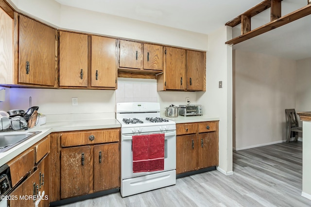 kitchen featuring sink, light hardwood / wood-style floors, and gas range gas stove