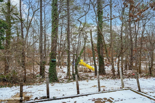 snowy yard featuring a playground